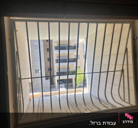 סורג ממתכת לבנה עם בטן המותקן בחלון דירה